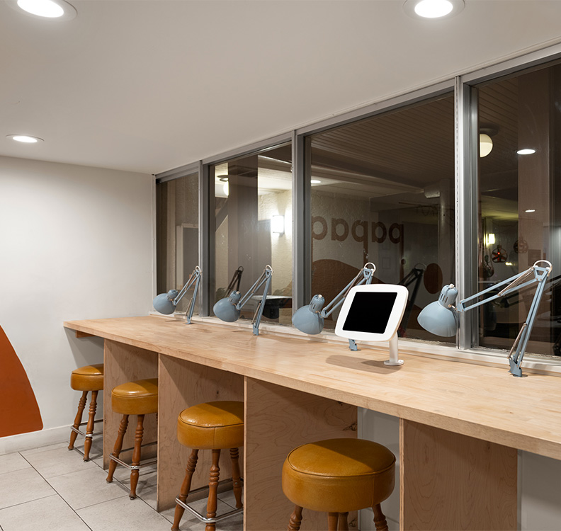 a desk with stools and a tablet on it