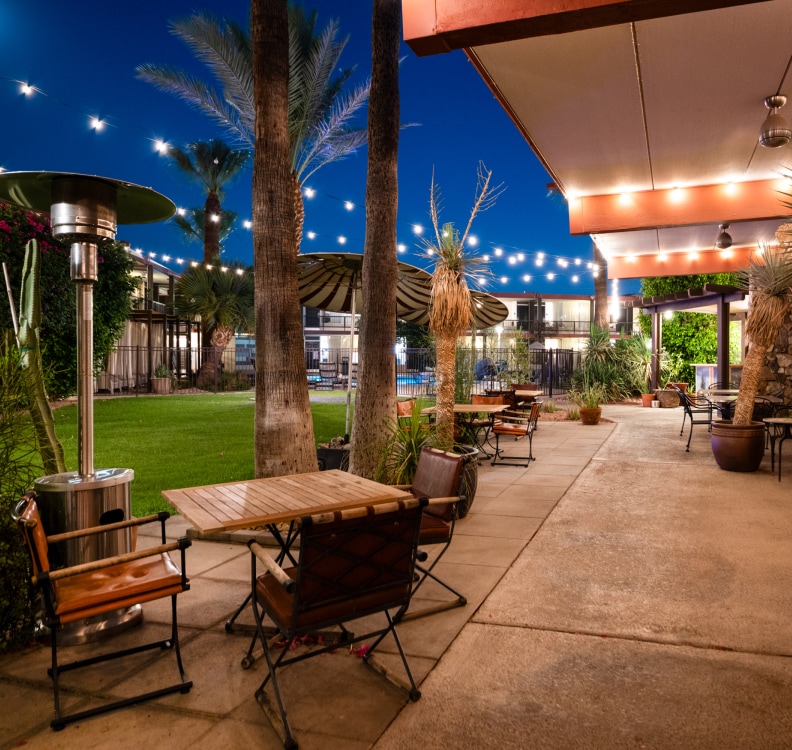 a patio with tables and chairs and trees