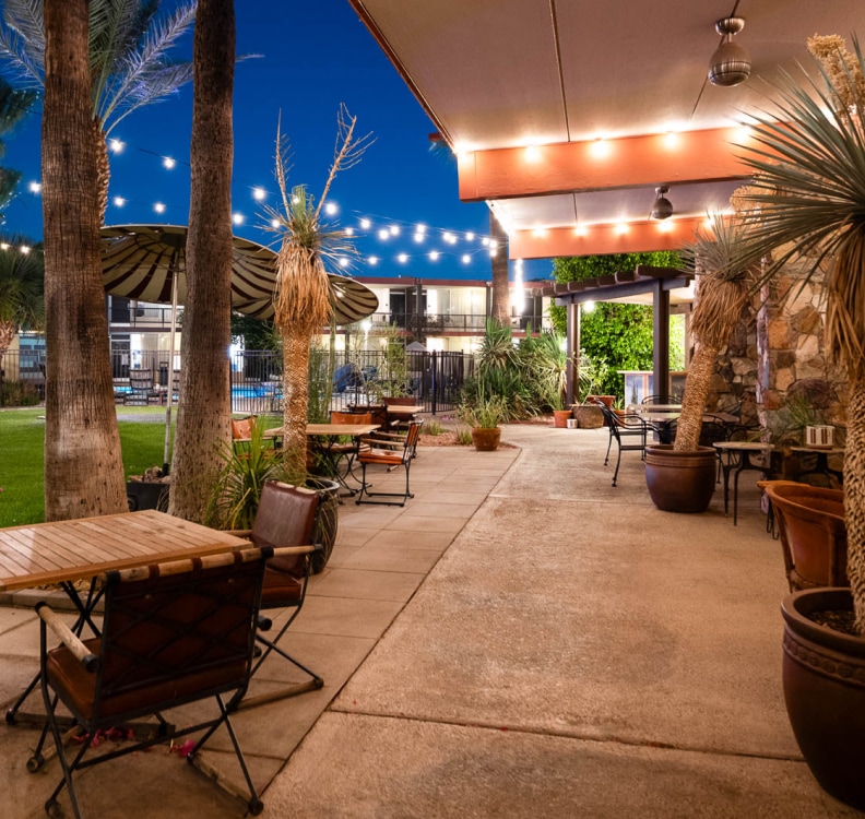 a patio with tables and chairs and trees