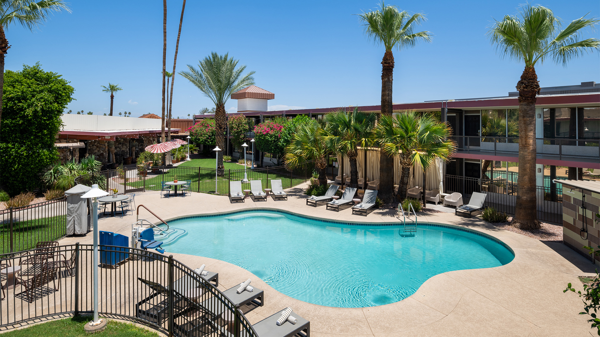 a pool with chairs and umbrellas by a building