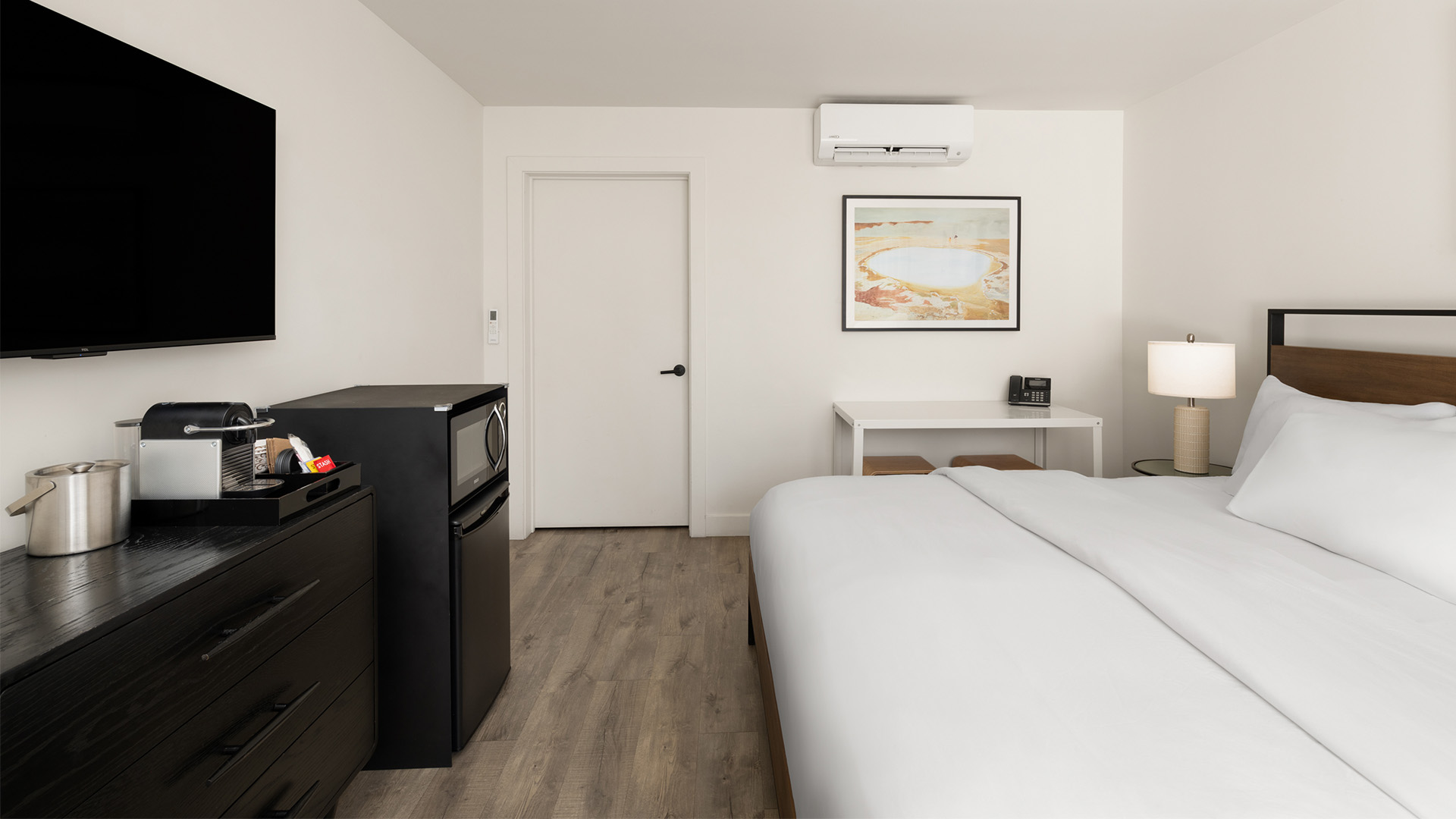 a bedroom with a white bed and a black microwave