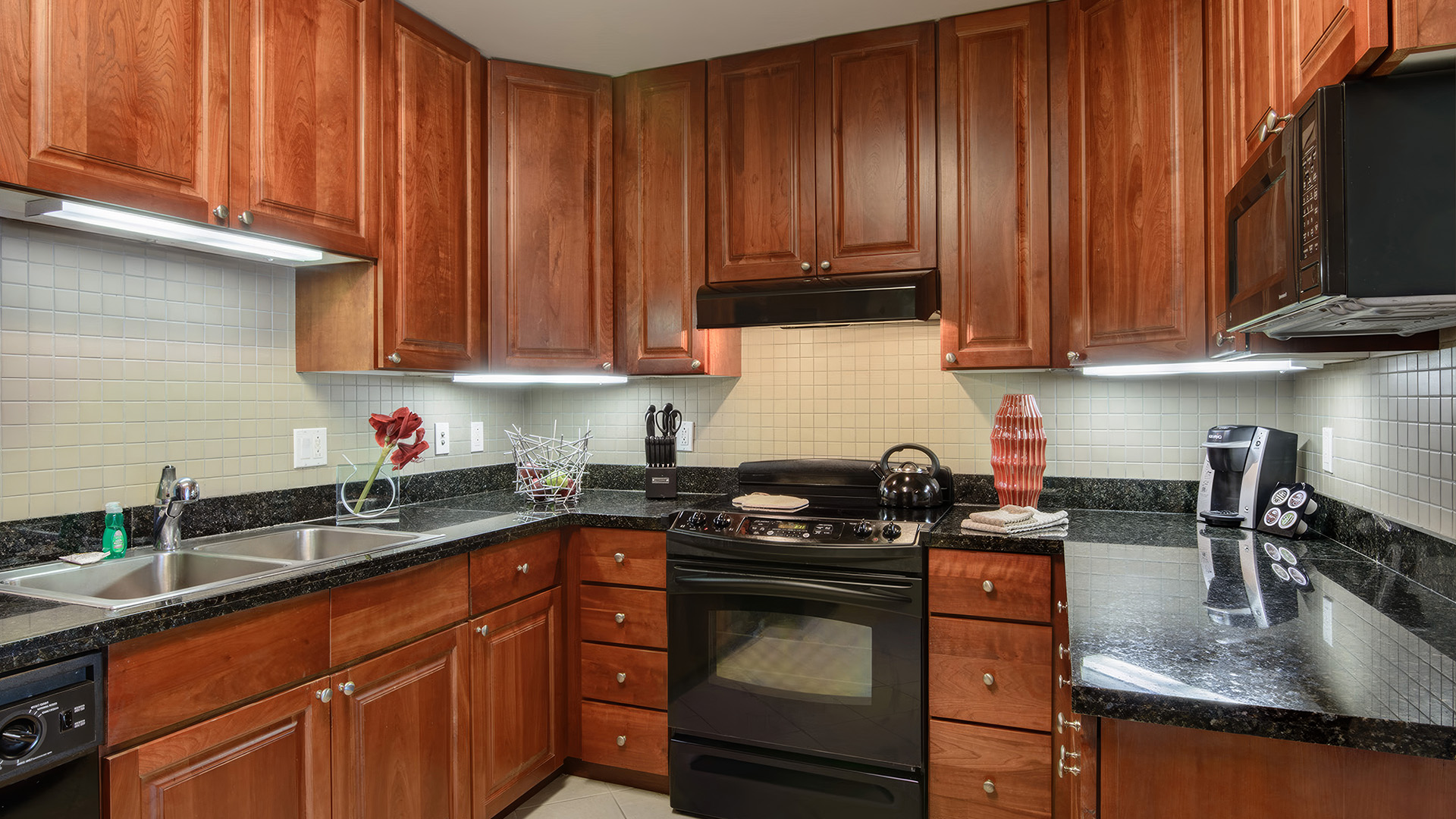 a kitchen with black counter tops and wooden cabinets