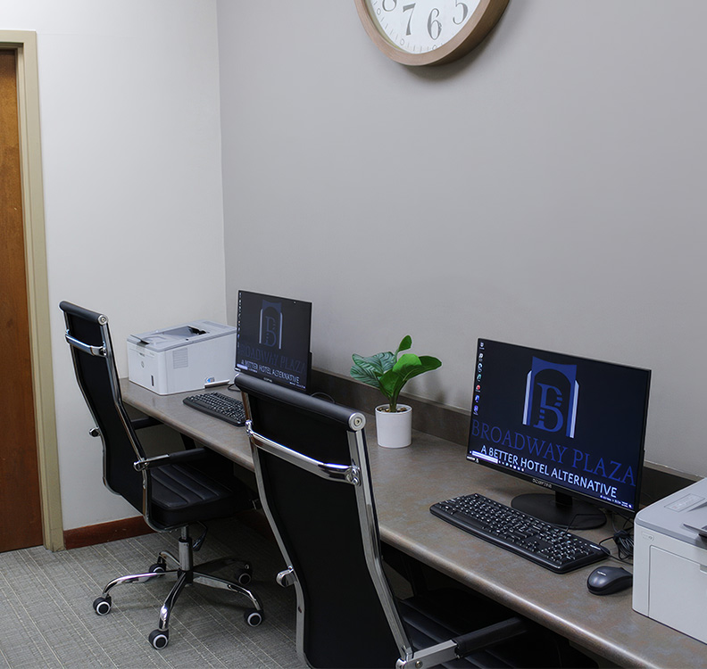 a desk with computers and chairs in front of a clock