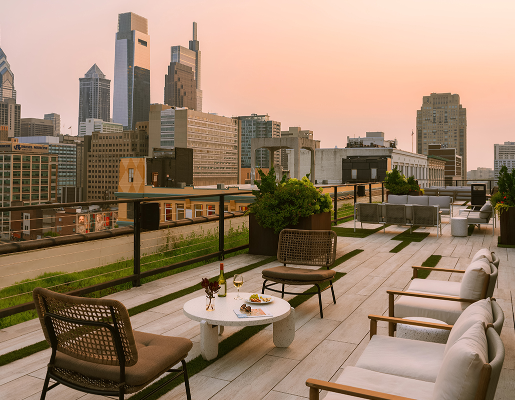 a rooftop patio with chairs and a table and a city skyline
