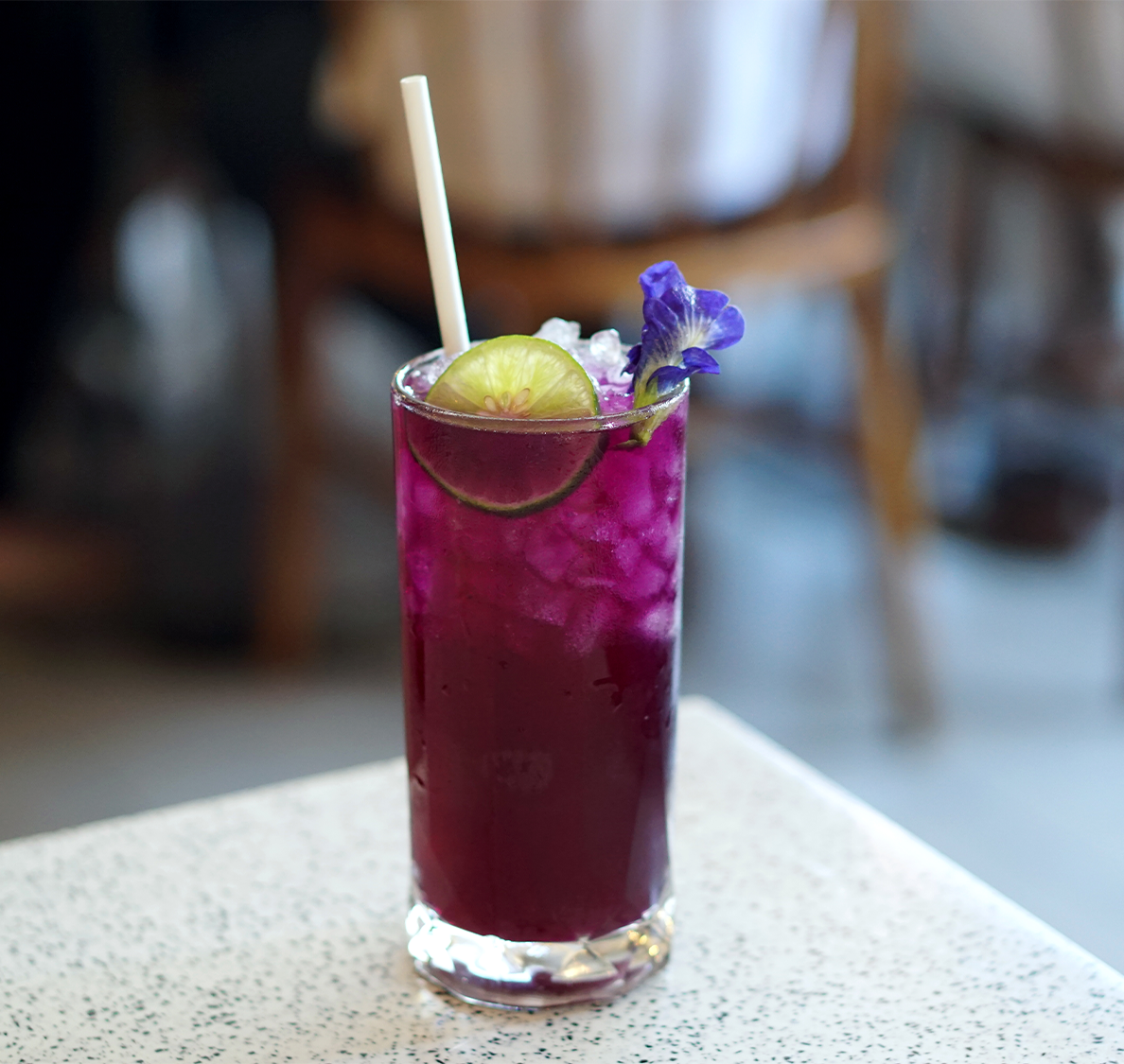a glass with purple liquid and lime slices