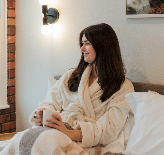 a woman sitting in a bed holding a cup