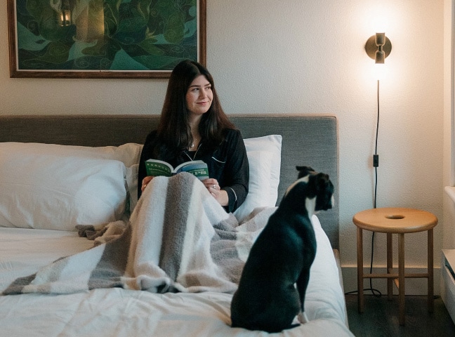 a woman sitting on a bed with a dog