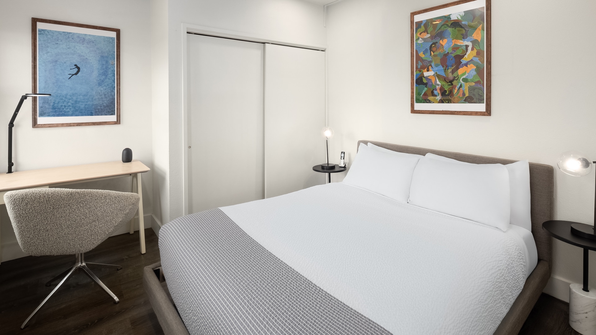a bed with a white blanket and a painting on the wall