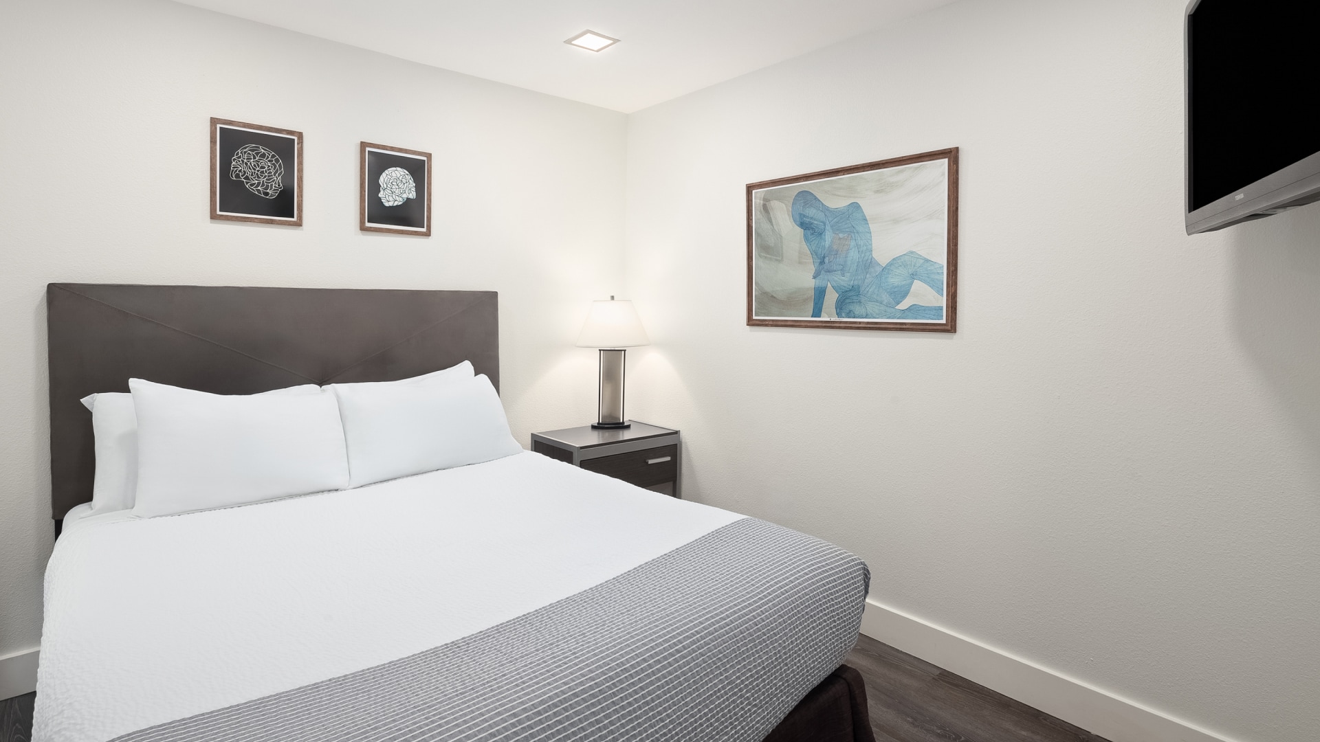 a bed with a lamp and a picture on the wall