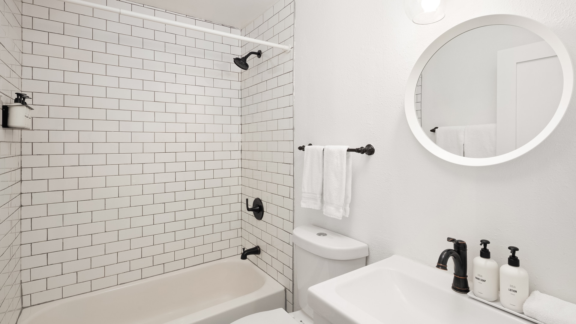 a bathroom with a white tile wall and a white toilet