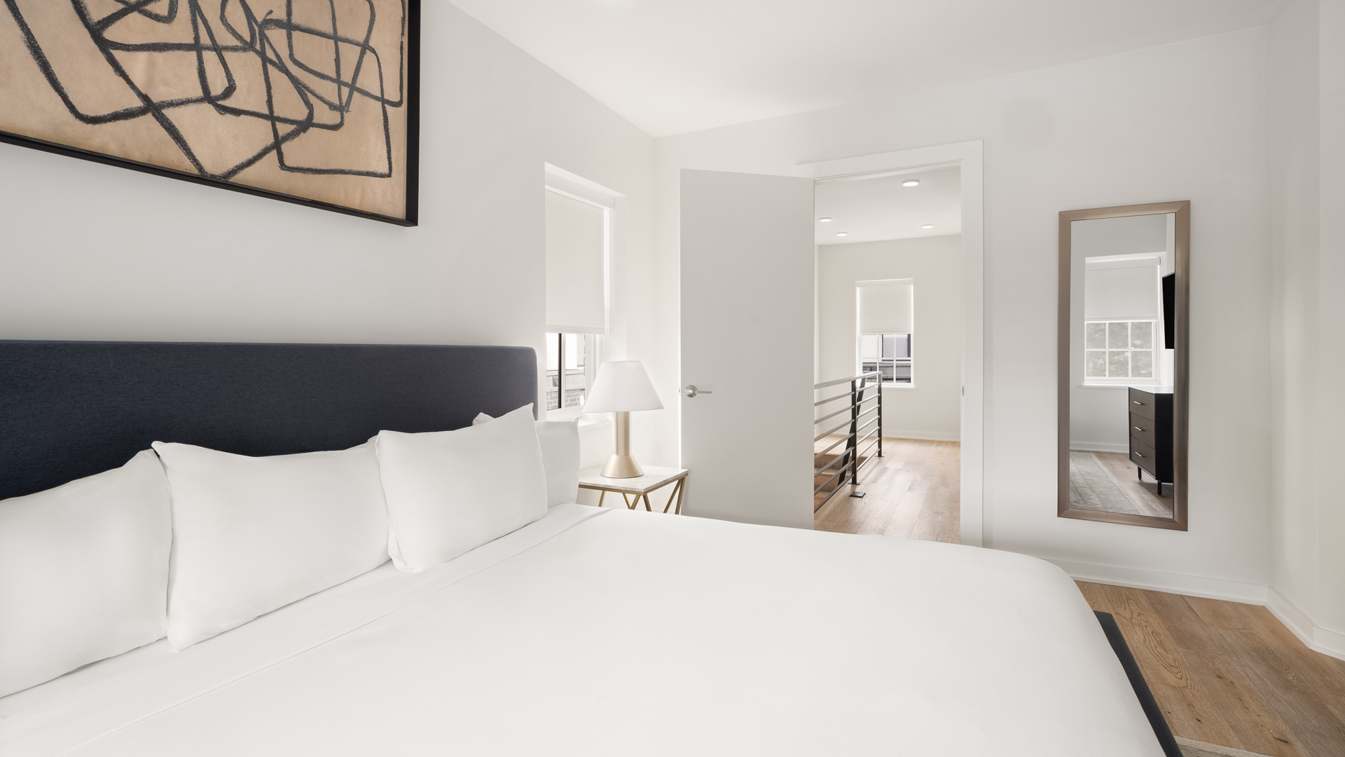 a white bed with white sheets and a lamp in a room