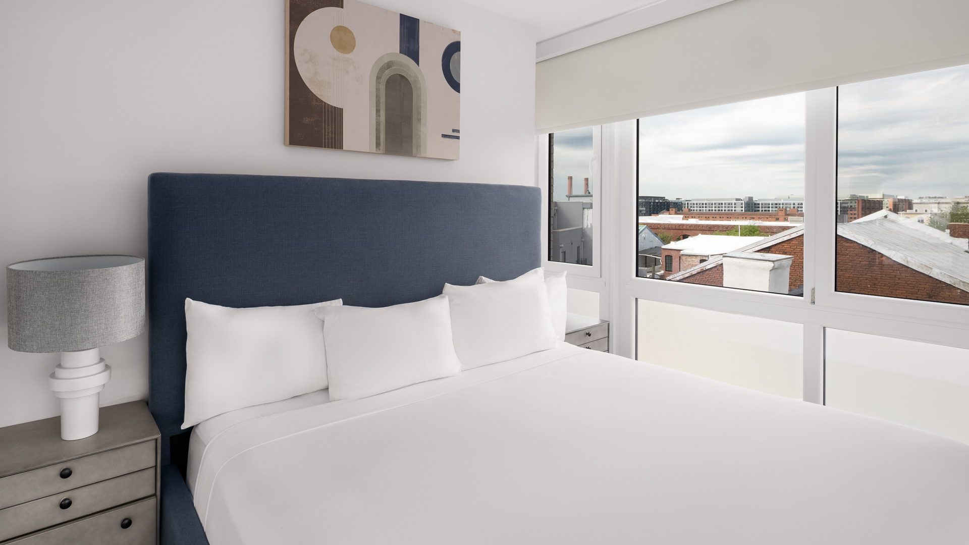 a bed with white sheets and pillows in a room with windows