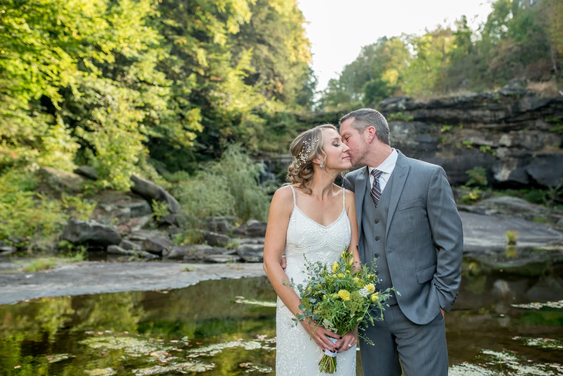 a man and woman kissing in front of a pond