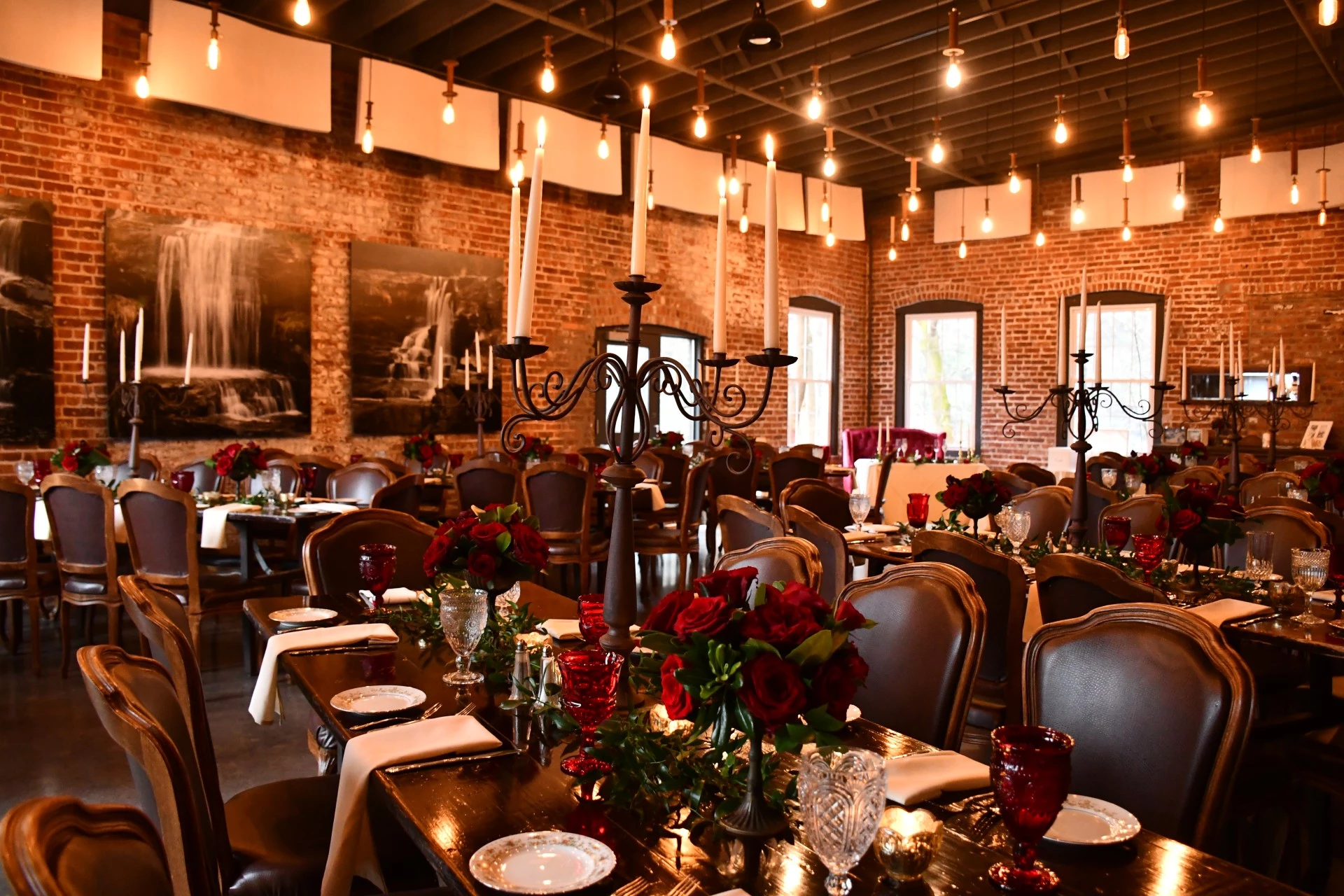 a room with a chandelier and tables with flowers