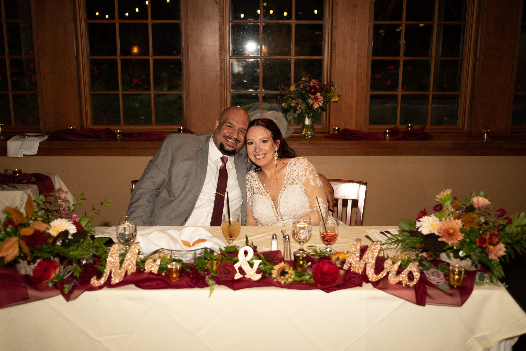 a man and woman sitting at a table with flowers and candles