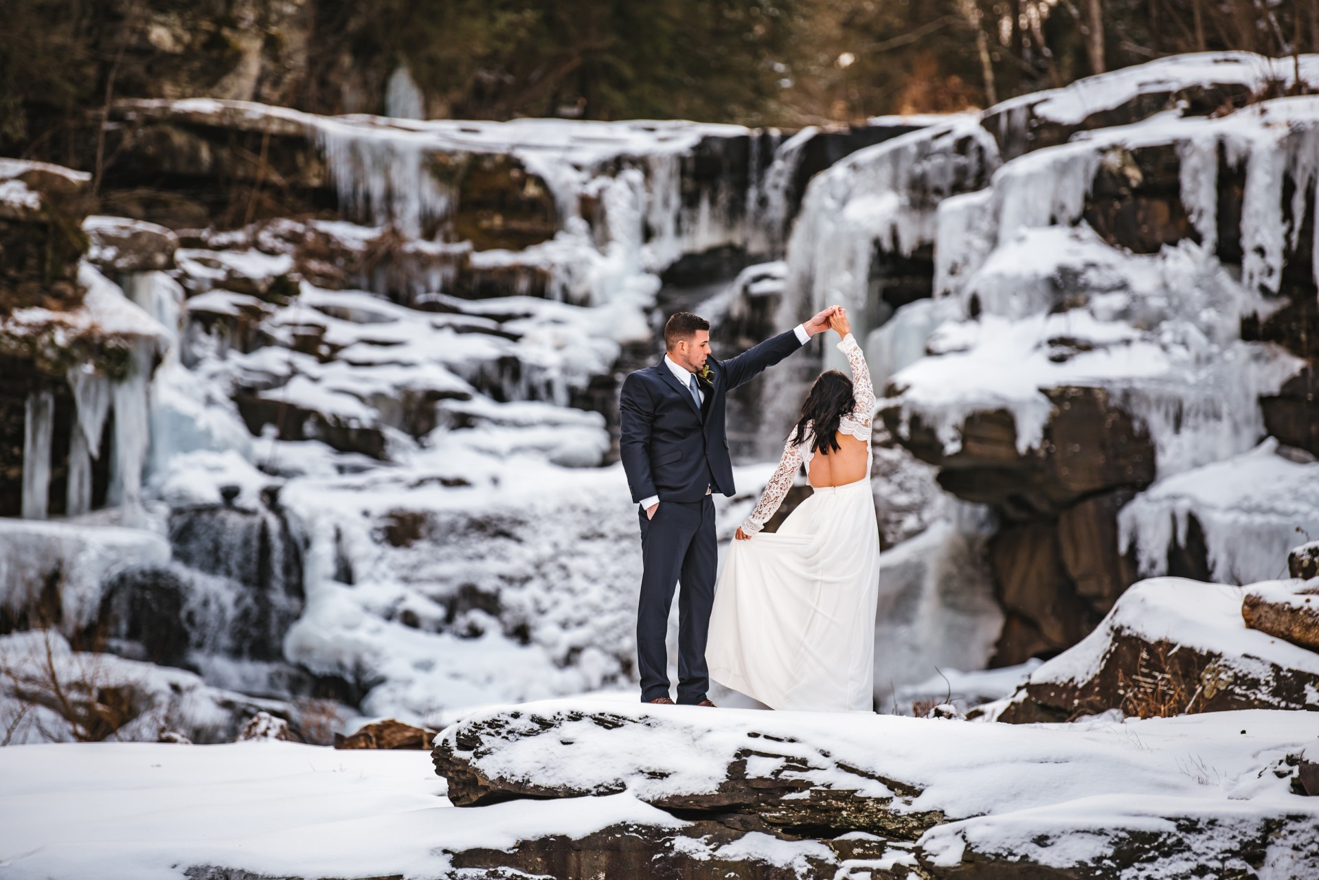 a man and woman in a suit and tie in front of a waterfall