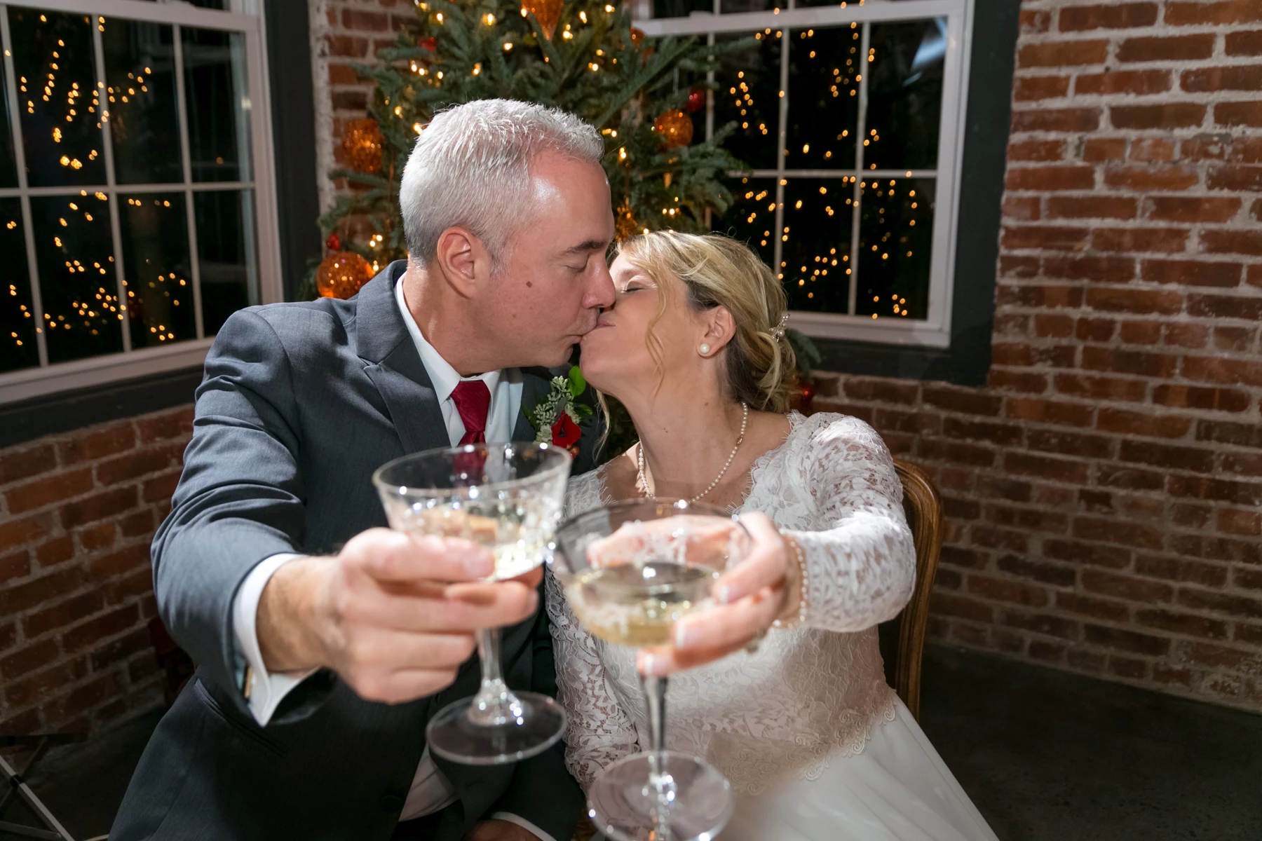 a man and woman kissing while holding wine glasses