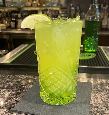 a glass with a green drink and lime wedge