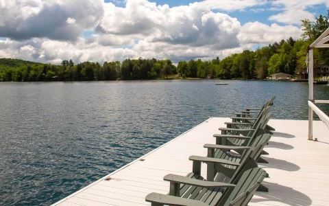 a row of chairs on a dock by a lake