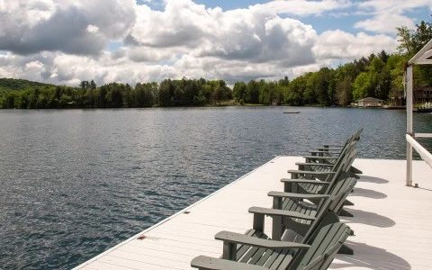 a row of chairs on a dock overlooking a lake