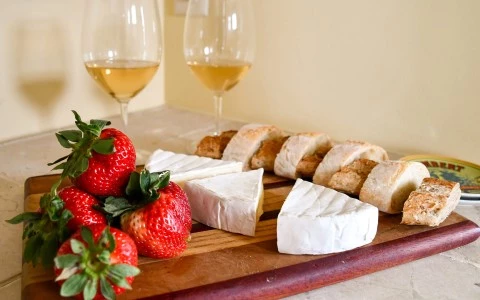 a cheese and strawberries on a cutting board