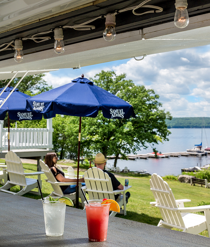a table with drinks on it and people sitting at tables with umbrellas and water