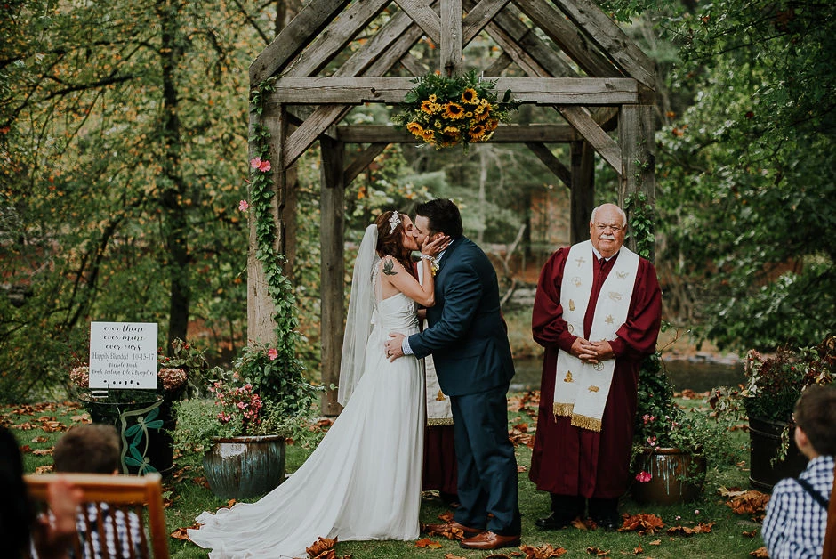a man and woman kissing under a wooden arch