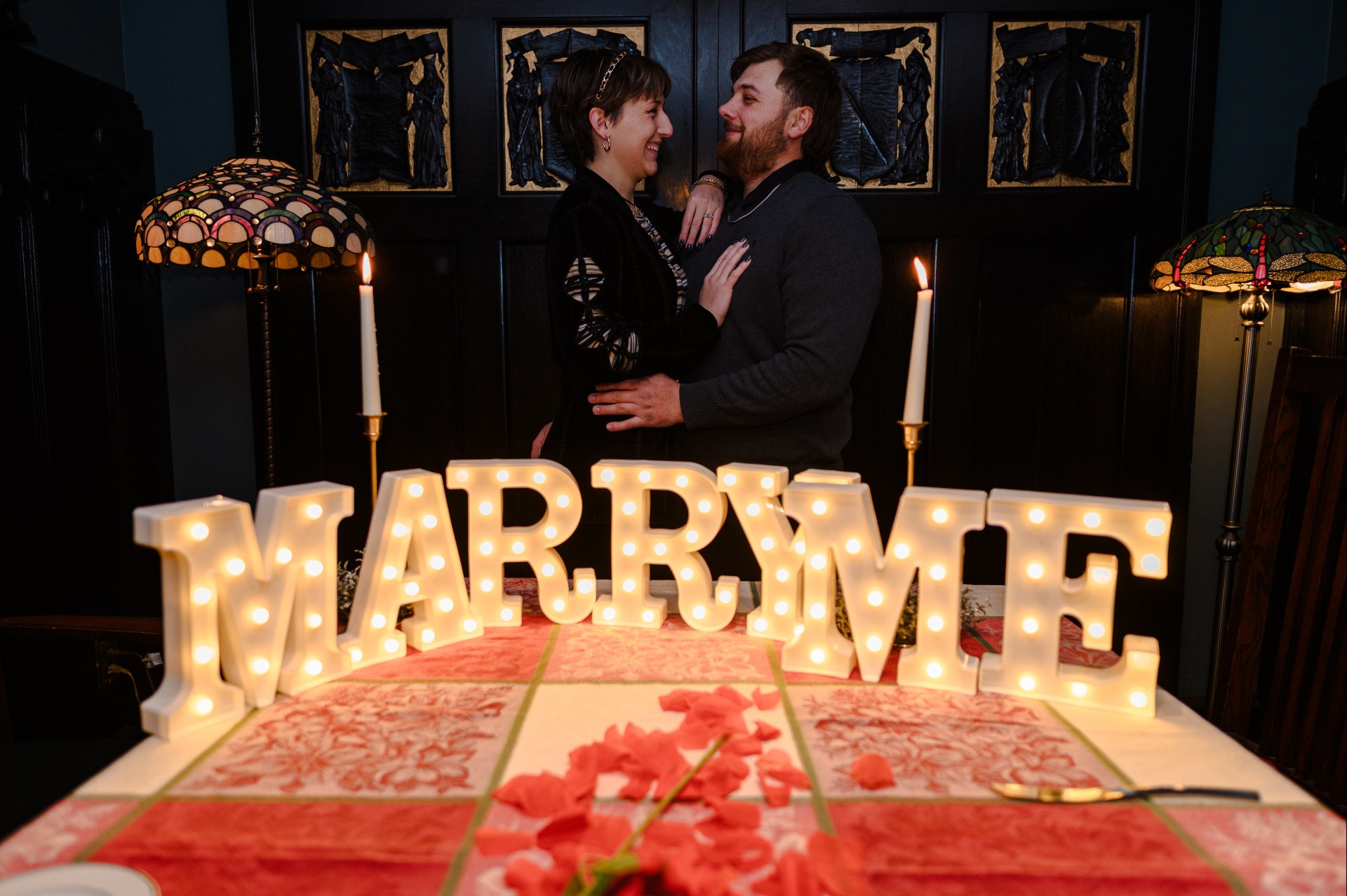 a man and woman standing next to a table with lit letters