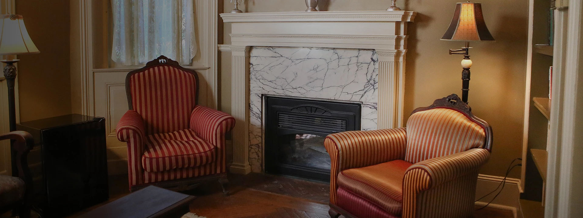 a fireplace with a marble fireplace and two chairs