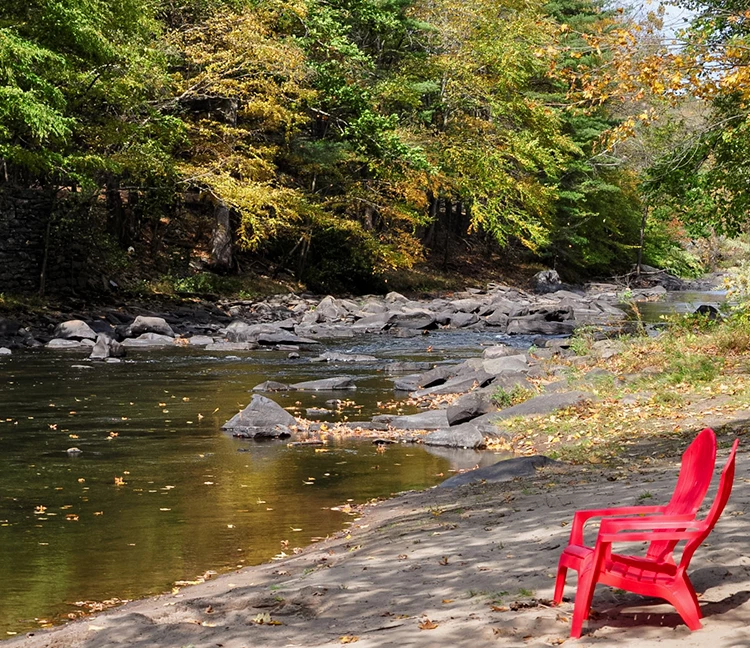 a red lawn chairs on a beach next to a river