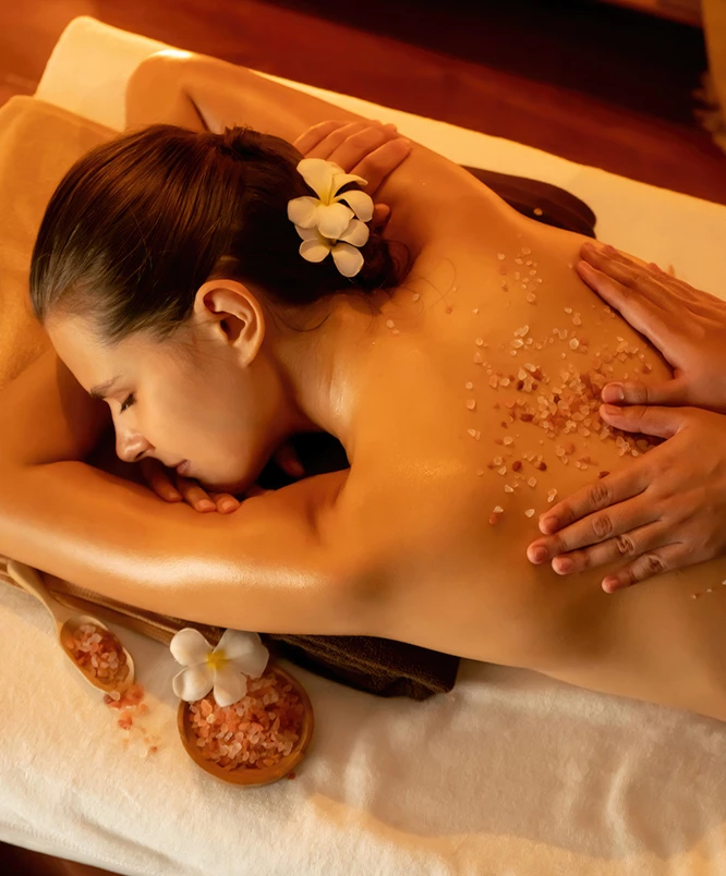 a woman lying down on a massage table with salt on her back