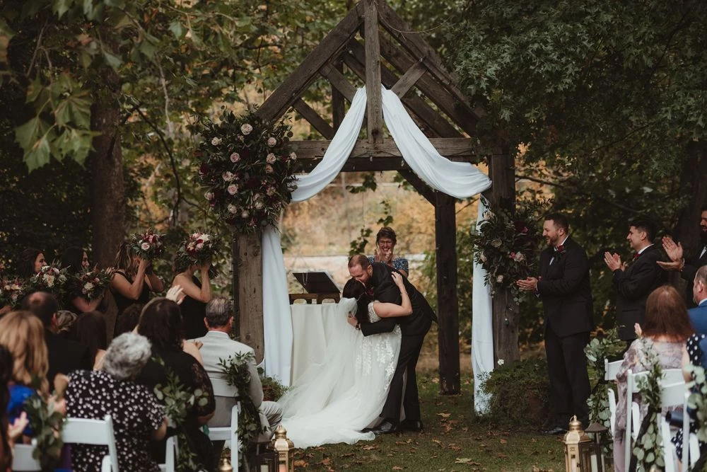 a man hugging a woman under a wooden arch