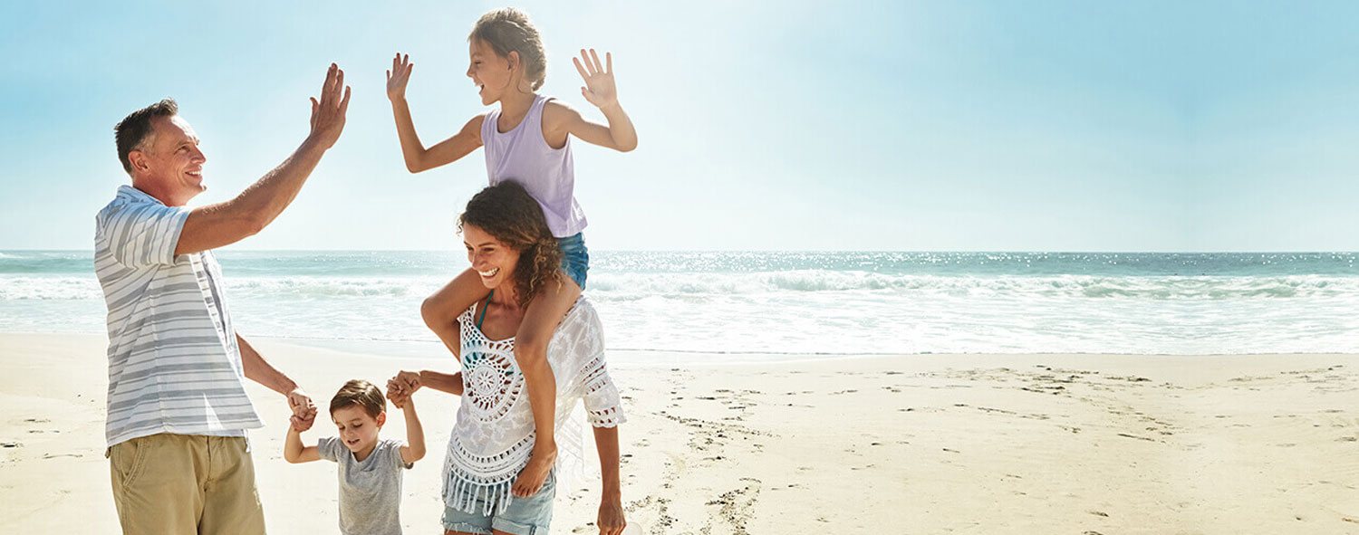 Couple with two kids holding hands while running along ocean shore