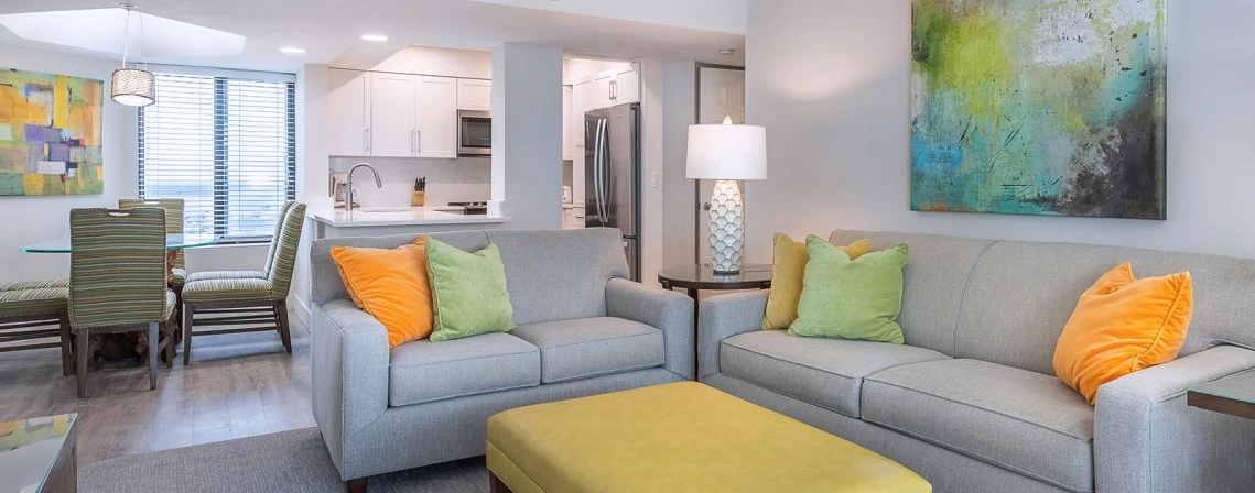 a living room with couches and a yellow ottoman