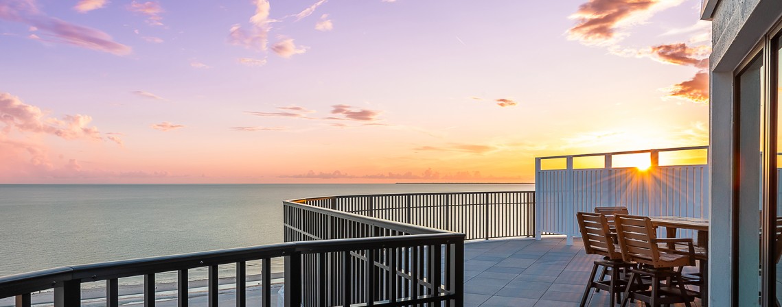 a deck with chairs and railings overlooking the ocean