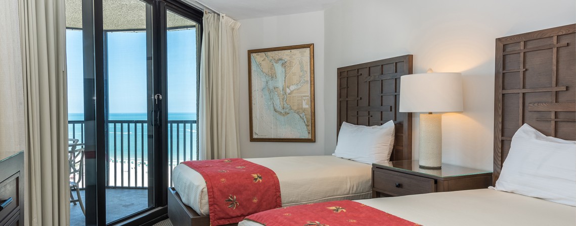 a bedroom with two beds and a glass door