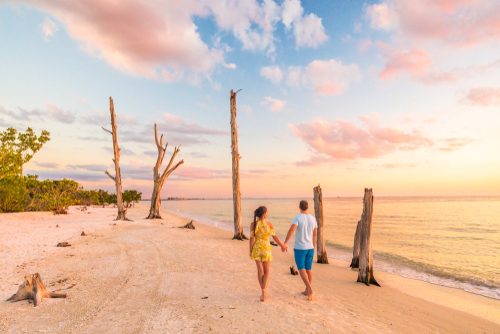 couple walking on beach at sunset