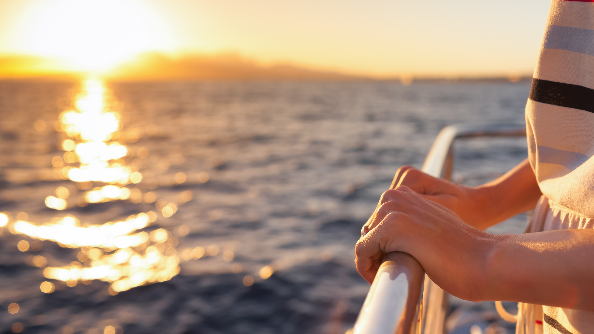 a hand on a railing over water