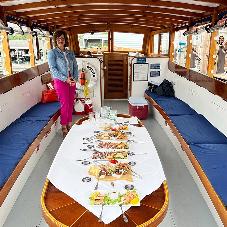 a woman standing in a boat with food on the table