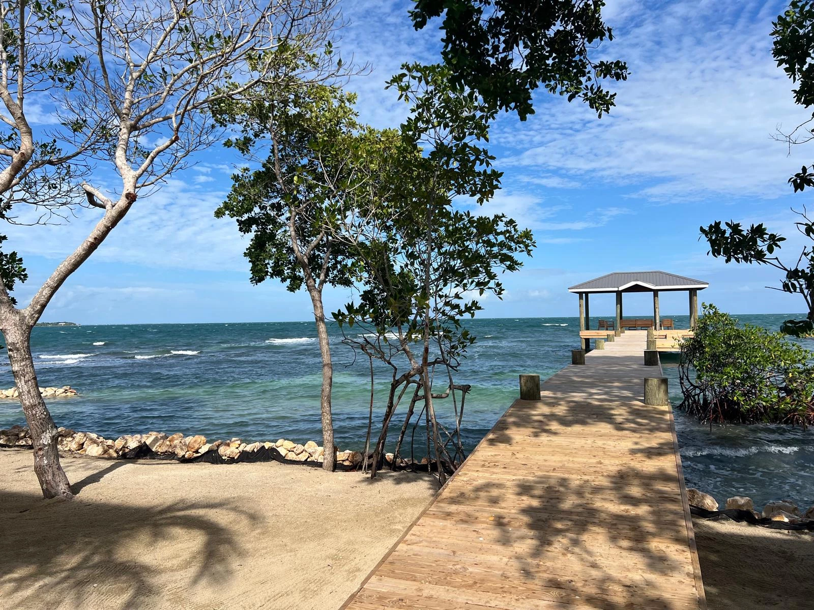 a dock with trees and a gazebo on the water