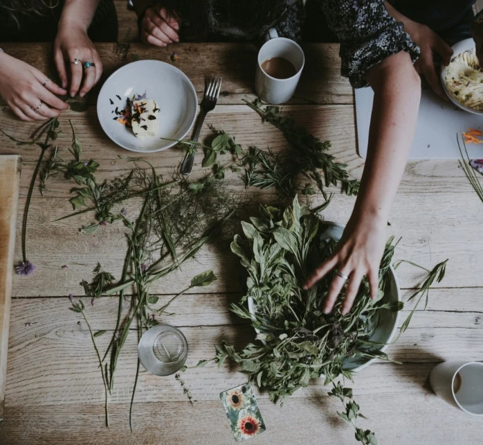 a group of people sitting around a table with food and plants