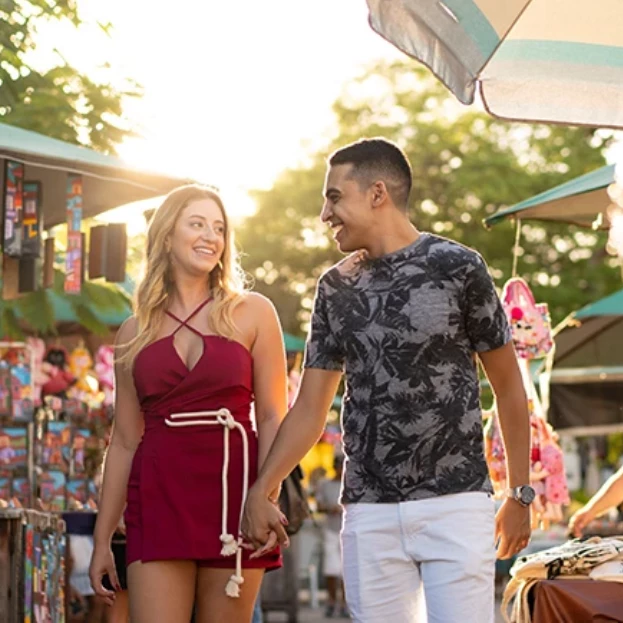 a man and woman holding hands and walking down a street
