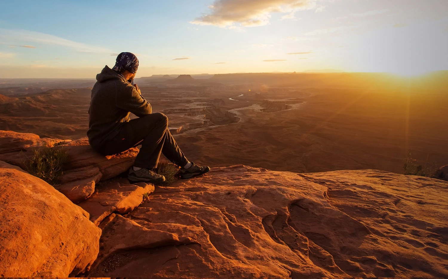 man atop a mountain watching the sun set