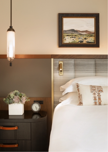 a bed with a clock and a plant on the side table