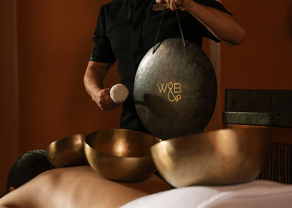 a person holding a gong over a group of bowls