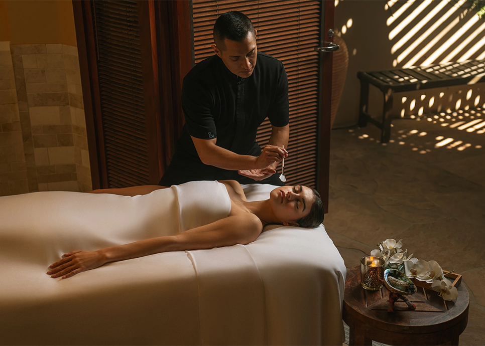 a man holding a stick to a woman lying on a bed