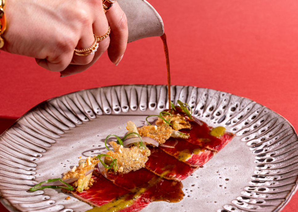 a person pouring sauce on a plate