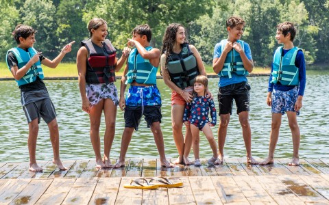 a group of people standing on a dock with life jackets