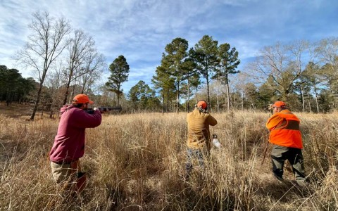 a group of men shooting in a field