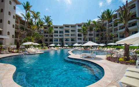 a swimming pool with umbrellas and palm trees